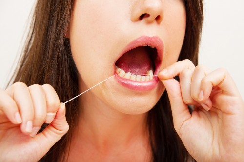 woman flossing to maintain a health mouth